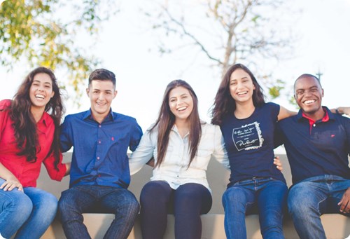 A group of young people sitting together smiling.