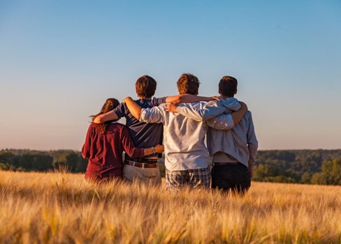 A group of people hugging in a field.